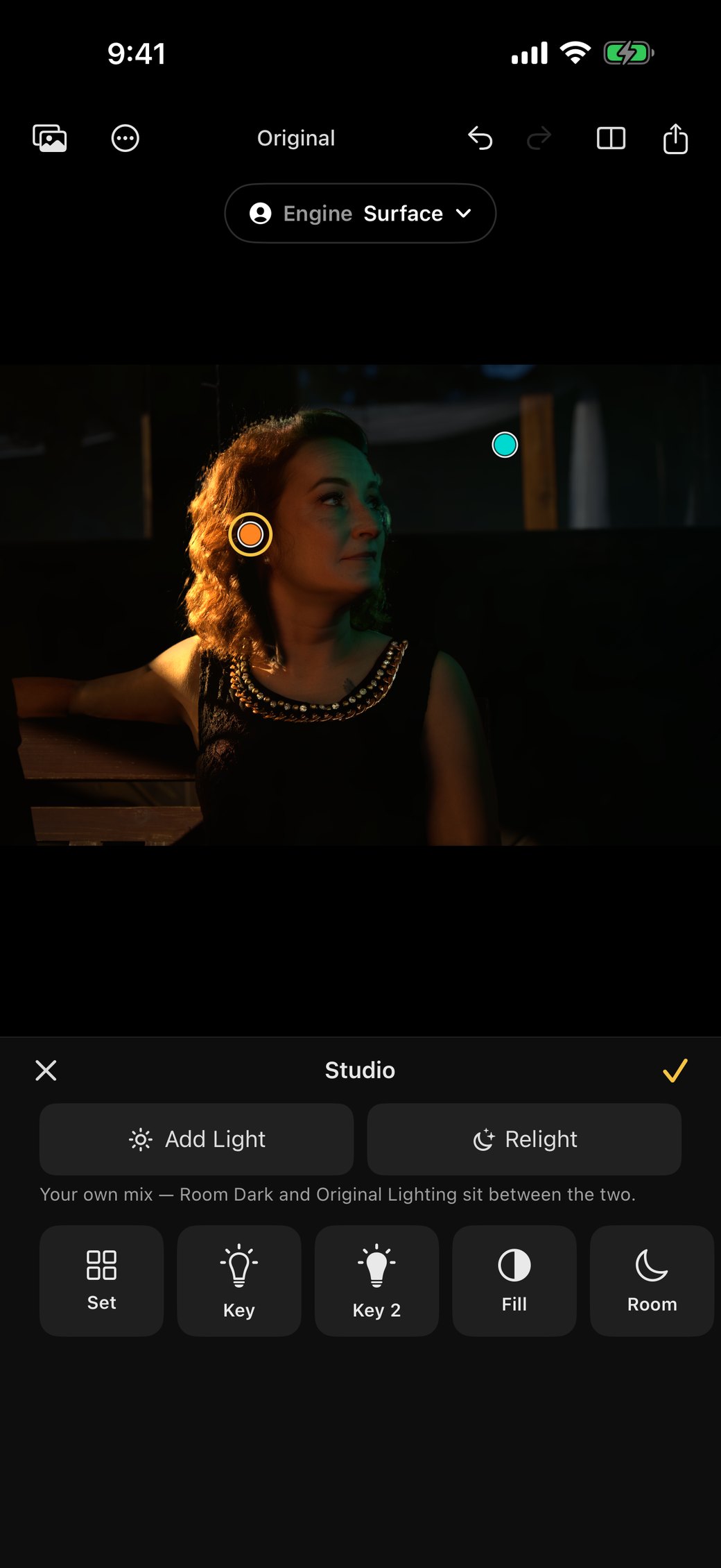 Rebrilo on an iPhone: a red-haired woman in a dark room, lit warmly from the left, with two lamp markers on the photograph. Under it the Studio: Add Light and Relight, and buttons for Set, Key, Key 2, Fill and Room.